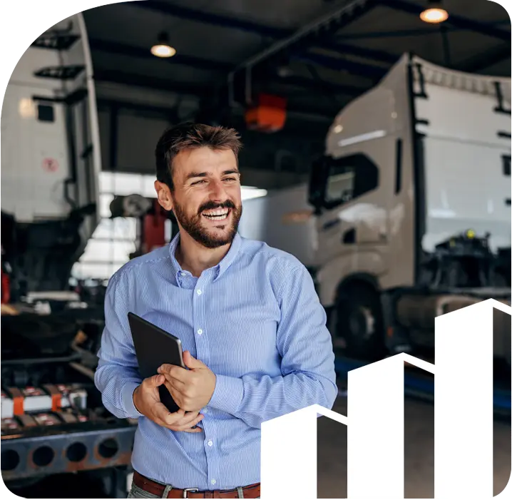 A man standing behind tractor trailer trucks holding a tablet.